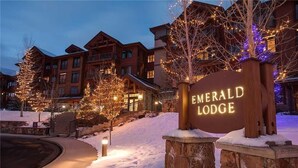 L’entrée d’Emerald Lodge, recouverte de neige, est agrémentée d’un panneau lumineux et d’arbres illuminés.