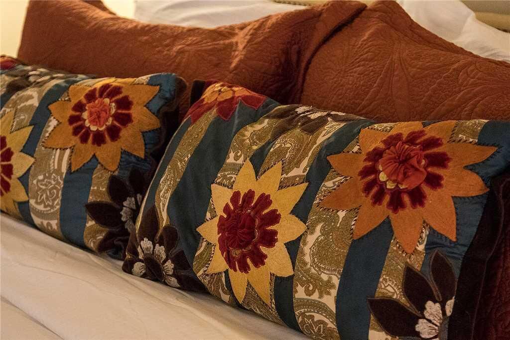 A bed with a white headboard and multiple pillows with floral patterns.
