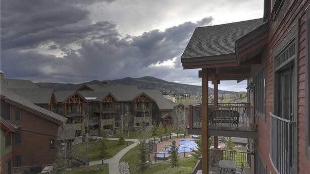 Un edificio de varios pisos con piscina, mobiliario exterior y vistas a montañas.