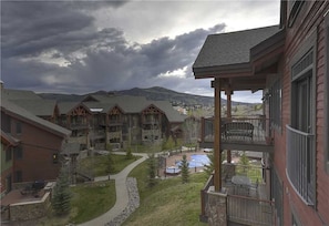 A multi-story building with a pool, outdoor seating, and a view of mountains. - 5203 Emerald Lodge, Trappeur's Crossing Apartment 4 (Steamboat Springs)