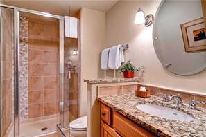 A bathroom with a shower, toilet, sink, and vanity.