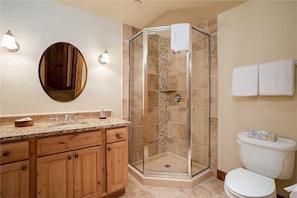 A bathroom with a shower, toilet, and vanity with a mirror.