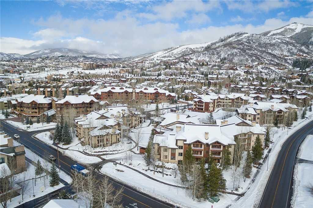 Une ville enneigée avec de nombreux bâtiments, des routes et une montagne en arrière-plan.