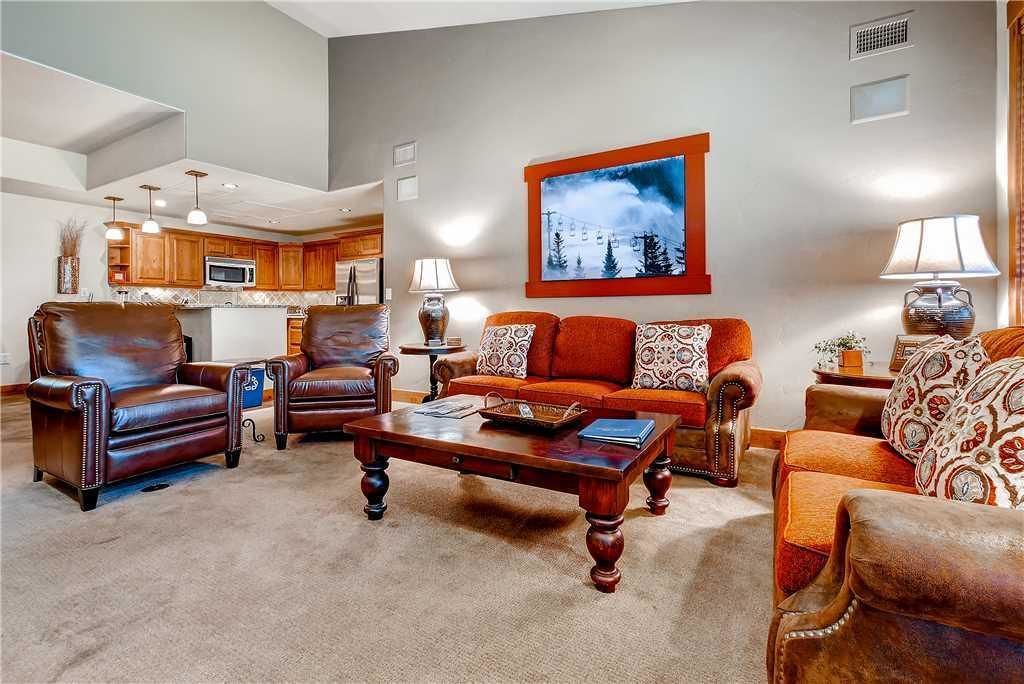 A living room with leather sofas, a coffee table, and a painting on the wall.
