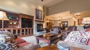 A spacious living room with a fireplace, leather sofas, a coffee table, and a television. - 5306 Emerald Lodge, Trappeur's Crossing Apartment 4 (Steamboat Springs)