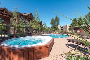 A hotel with a hot tub, lounge chairs, and a pool area. - 5307 Emerald Lodge, Trappeur's Crossing Apartment 4 (Steamboat Springs)