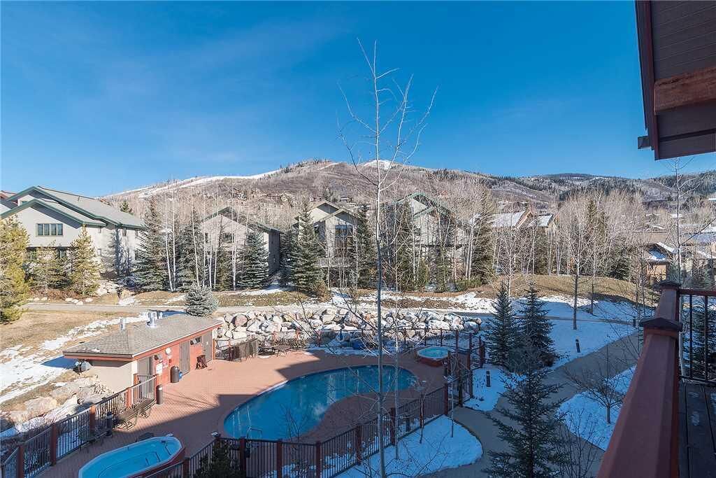A resort with a pool area, multiple buildings, and a mountainous backdrop.