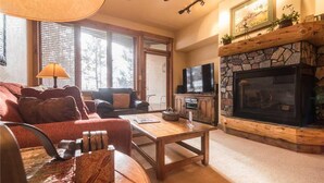 A cozy living room with a fireplace, a television, and a comfortable seating area. - 2101 Timberline Lodge, Trappeur's Crossing Apartment 2 (Steamboat Springs)