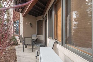 An outdoor patio with a table and chairs, a covered seating area, and a window with blinds.