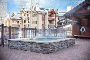 A spa area with a hot tub, stone steps, and a wooden deck. - 2103 Timberline Lodge, Trappeur's Crossing Apartment 2 (Steamboat Springs)