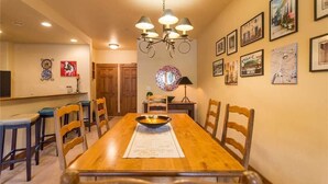 Un coin repas avec une table en bois, des chaises, un lustre et des tableaux encadrés accrochés au mur.