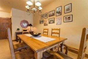 En matplats med ett träbord, fyra stolar, en kristallkrona och inramade tavlor på väggen.