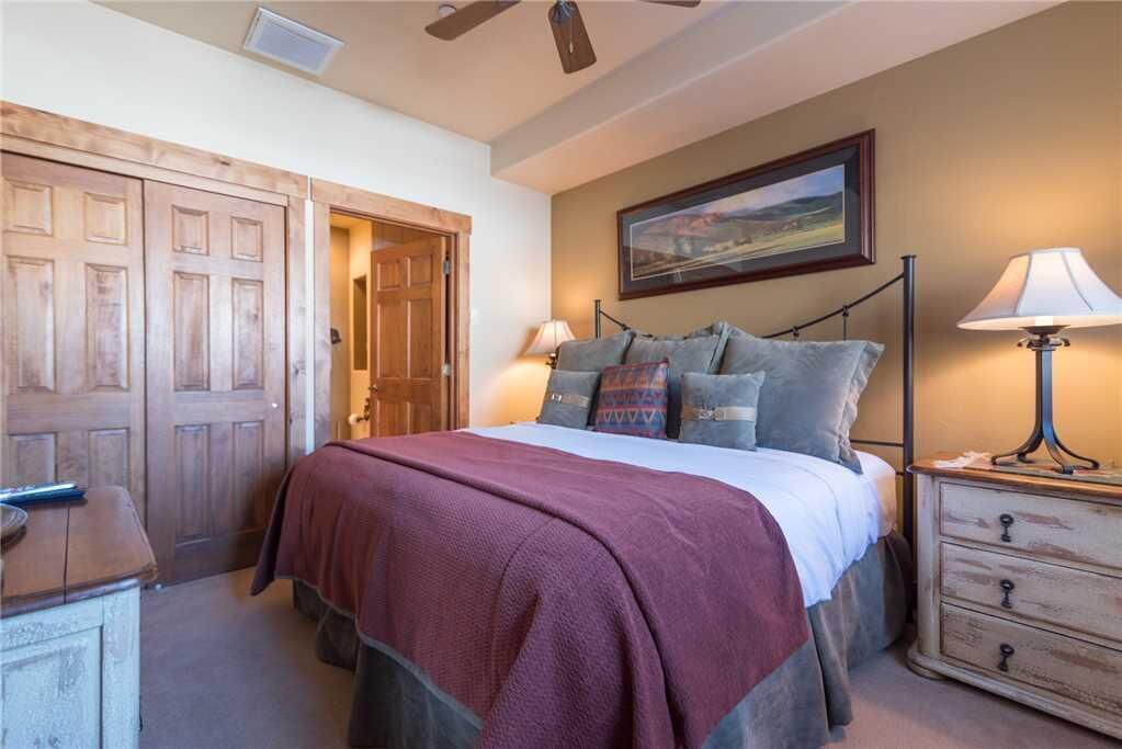 A bedroom with a bed, a nightstand, a dresser, and a ceiling fan.