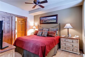 A bedroom with a bed, a television, a dresser, a ceiling fan, and a painting on the wall. - 2309 Timberline Lodge, Trappeur's Crossing Apartment 1 (Steamboat Springs)