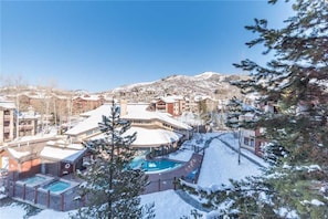 A resort with multiple buildings, a pool area, and a snowy mountain backdrop. - 2309 Timberline Lodge, Trappeur's Crossing Apartment 1 (Steamboat Springs)