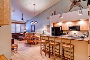 A modern kitchen with wooden cabinets, a microwave, and a coffee machine. There is a dining area with a table and chairs. - 2309 Timberline Lodge, Trappeur's Crossing Apartment 1 (Steamboat Springs)