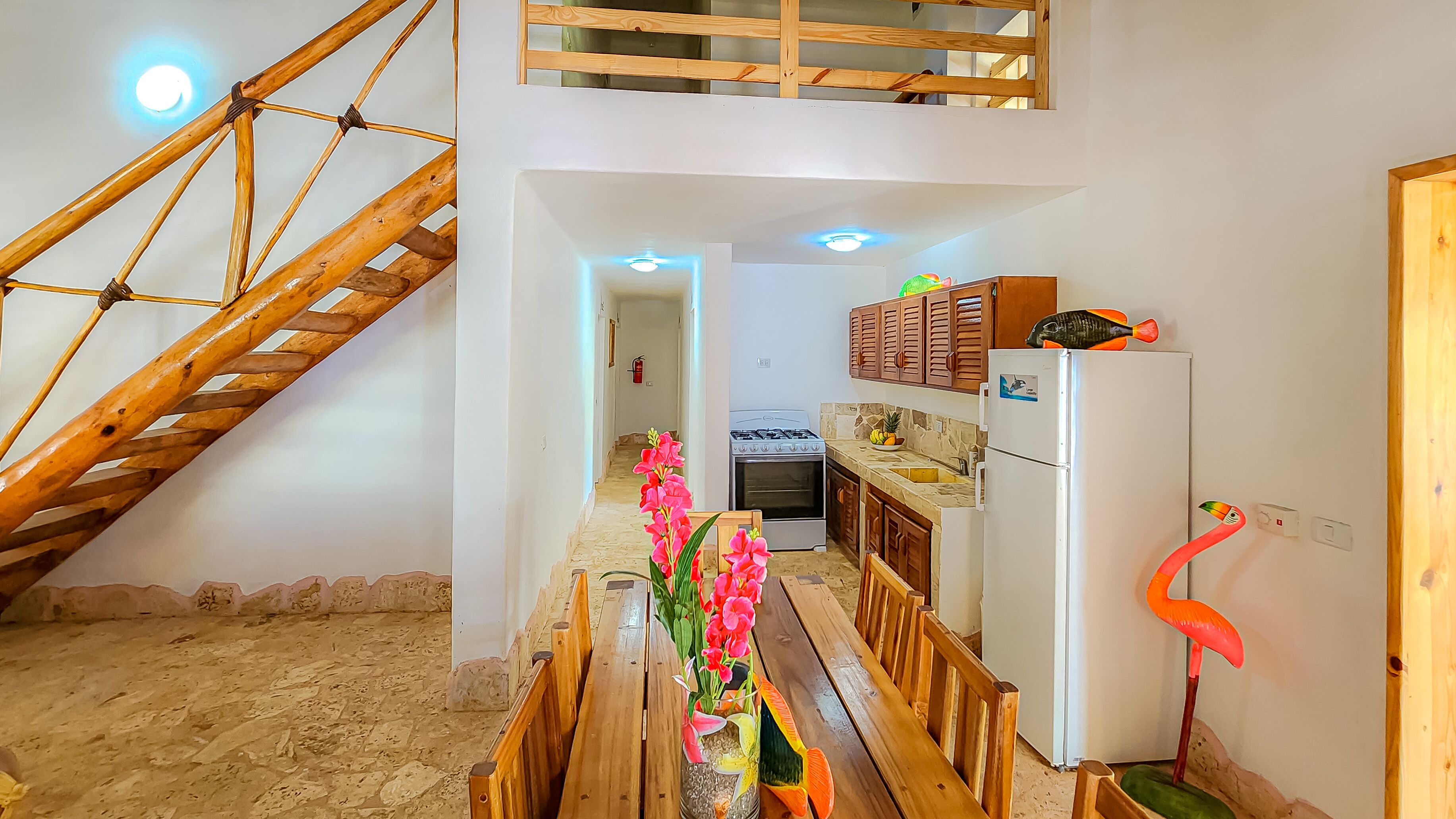 A kitchen with a wooden staircase, a white refrigerator, and a stove.