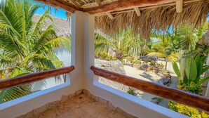 Ein Balkon mit Blick auf einen tropischen Garten, inklusive Palmen und Strand.