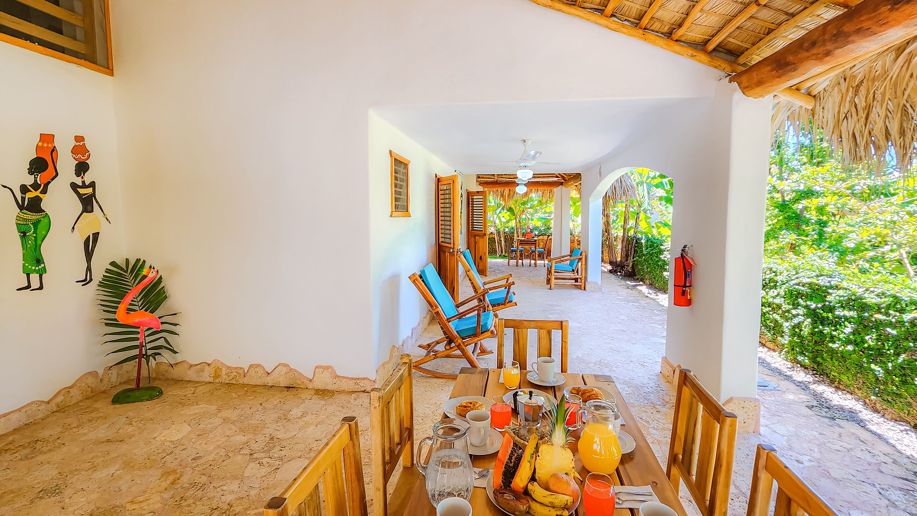 A dining area with a table set for breakfast, including tropical fruits and beverages.