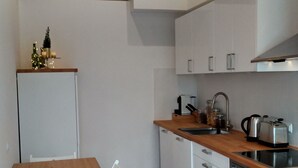 Een moderne keuken met witte kastjes, een houten eettafel en een bakstenen muur.