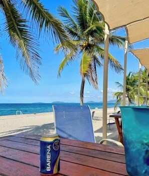 A beachside table with a can of Barena beer, a blue mesh chair, and a blue water container. - Holiday home Casa Lila (Tela)