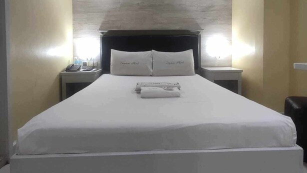 A hotel room with a large bed, two bedside tables with lamps, and a wooden headboard. - Bedbox Hotel (Manila)