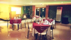 A restaurant with tables set for dining, a stage for performances, and a large air conditioning unit. - Bedbox Hotel (Manila)