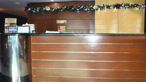 A reception desk with a wooden panel design, a glass partition, and a Christmas garland. - Bedbox Hotel (Manila)