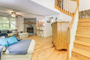 Amplia sala de estar con chimenea, escalera de madera y un rincón de descanso acogedor.