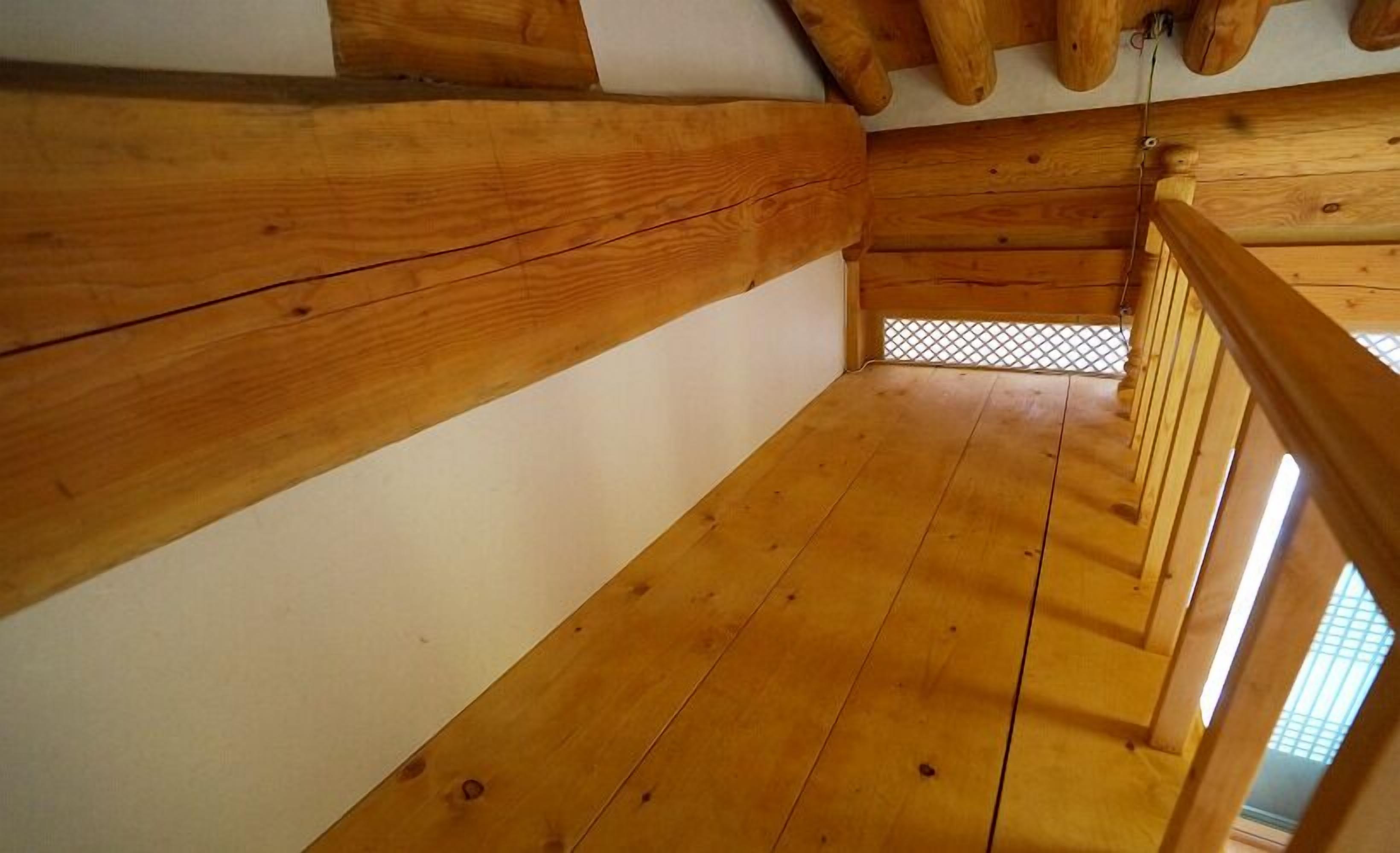 Een houten interieur met een schuine kap en uitzicht door een lattenraam.