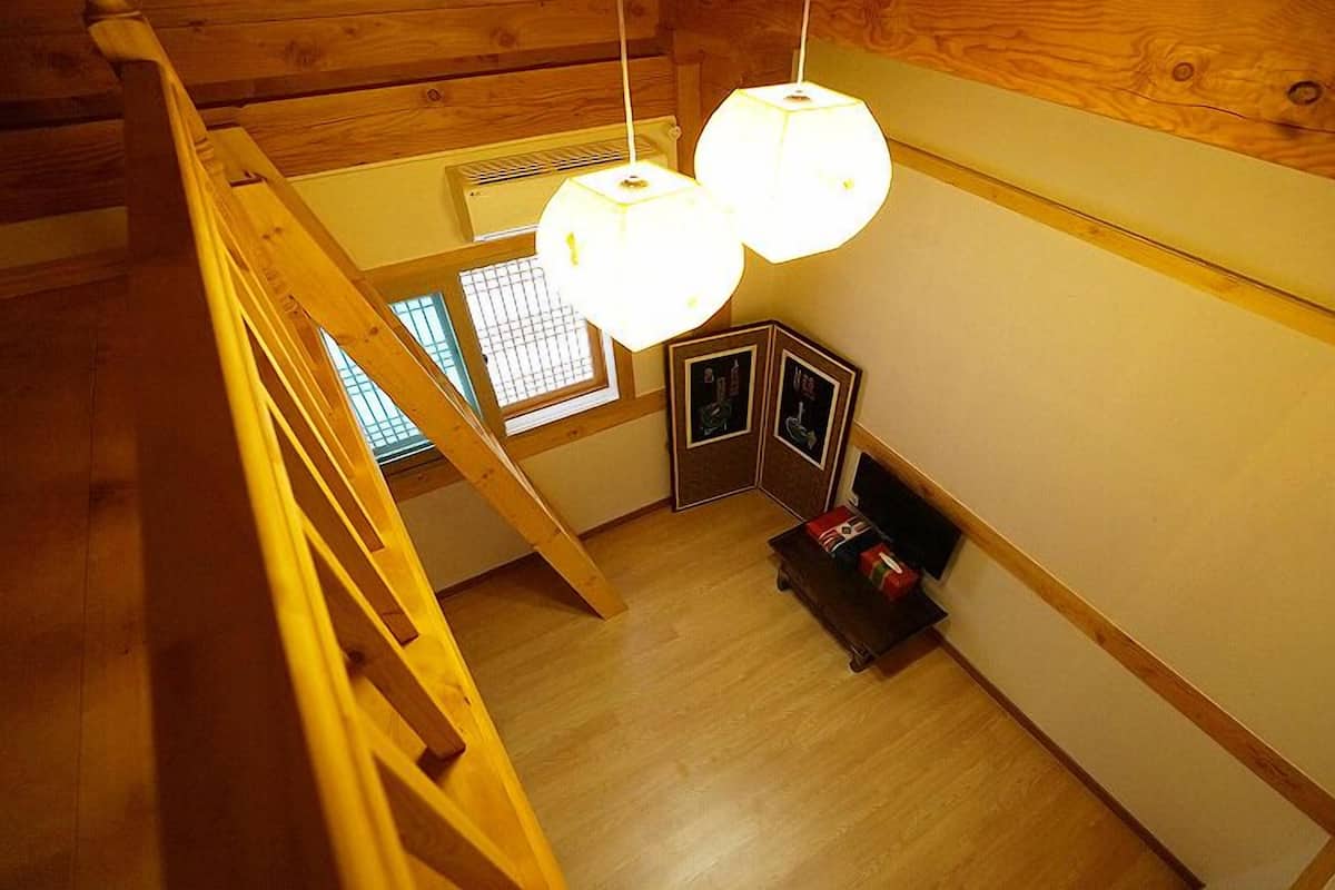 A wooden interior with a staircase, wooden beams, and a ceiling light fixture.