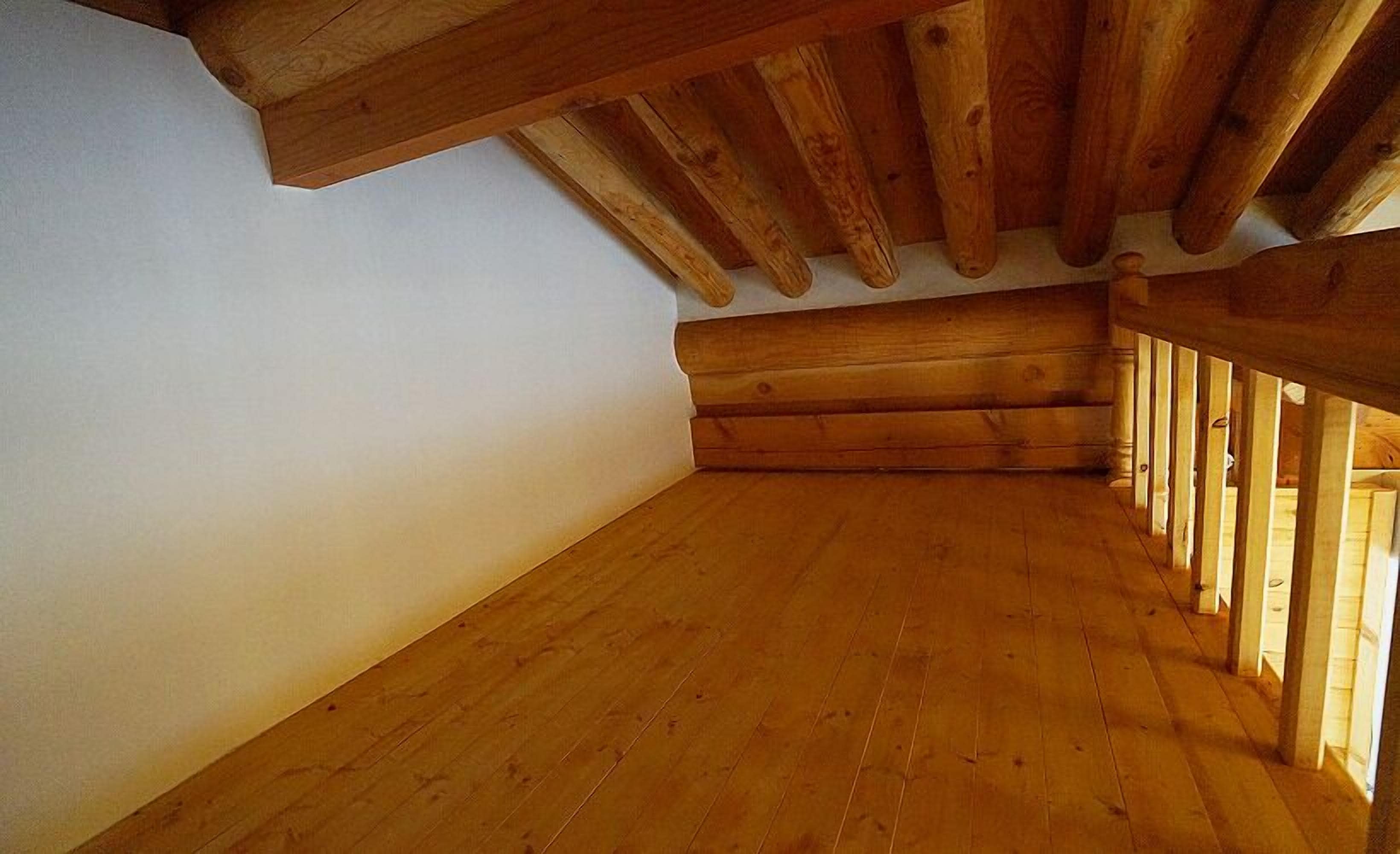 A room with wooden beams and a sloped ceiling, likely a loft or attic space.