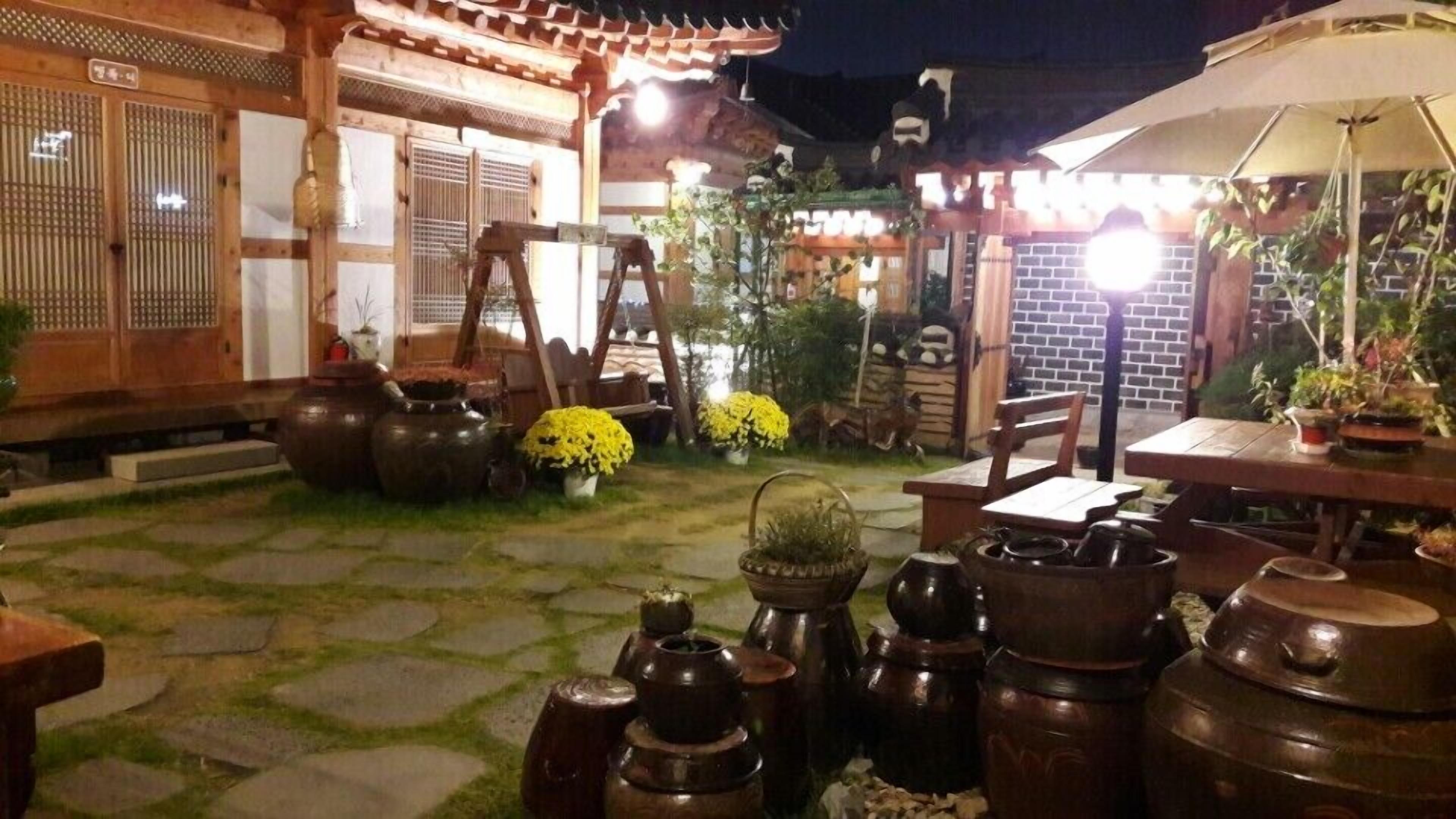 Un patio tradicional con suelo de piedra, muebles de madera y plantas en macetas.