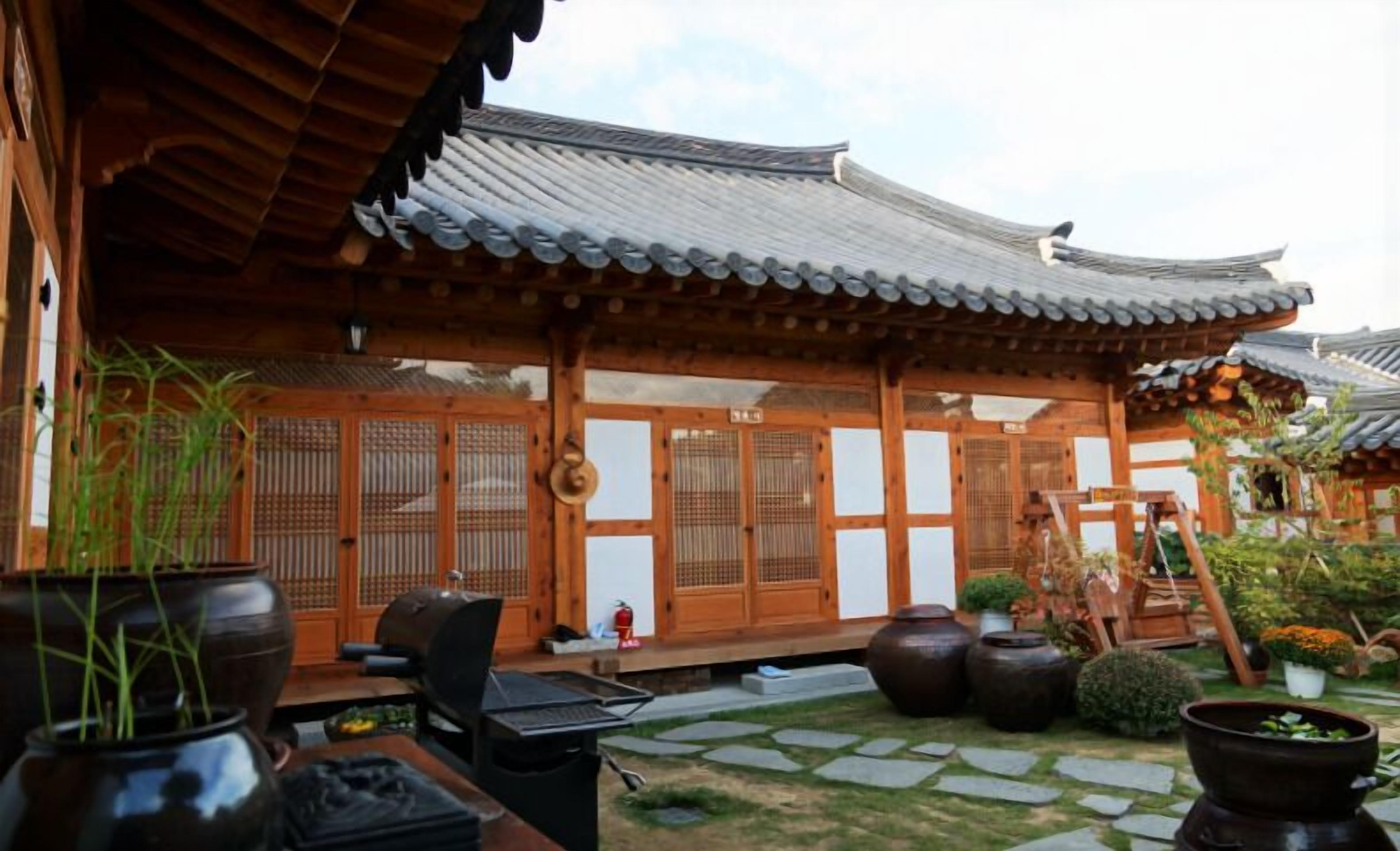 A traditional Korean-style building with wooden architecture, a tiled roof, and a stone pathway leading to the entrance.