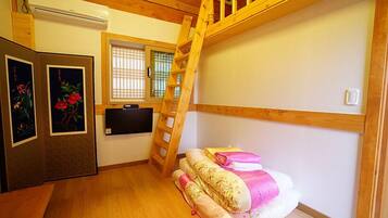 A small room with a bunk bed, a wooden ladder, a TV, and a window with blinds.