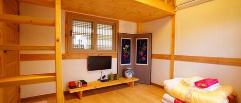 A wooden room with bunk beds, a TV, a shelf with items, and a door with floral decorations.