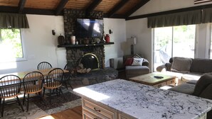 A cozy living room with a stone fireplace, a television mounted on the wall, and a comfortable seating area with a couch and chairs. - Great Vacation Destination, 1 Mile To Storyland, Skiing, Golf, Hiking. (Bartlett)