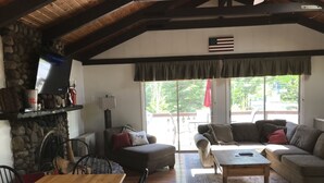 A cozy living room with a stone fireplace, wooden dining table, and comfortable seating. - Great Vacation Destination, 1 Mile To Storyland, Skiing, Golf, Hiking. (Bartlett)