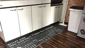 Une cuisine avec des meubles blancs, un plan de travail noir et un plancher en bois.