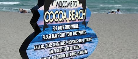 A beach sign with a message about preserving the environment.