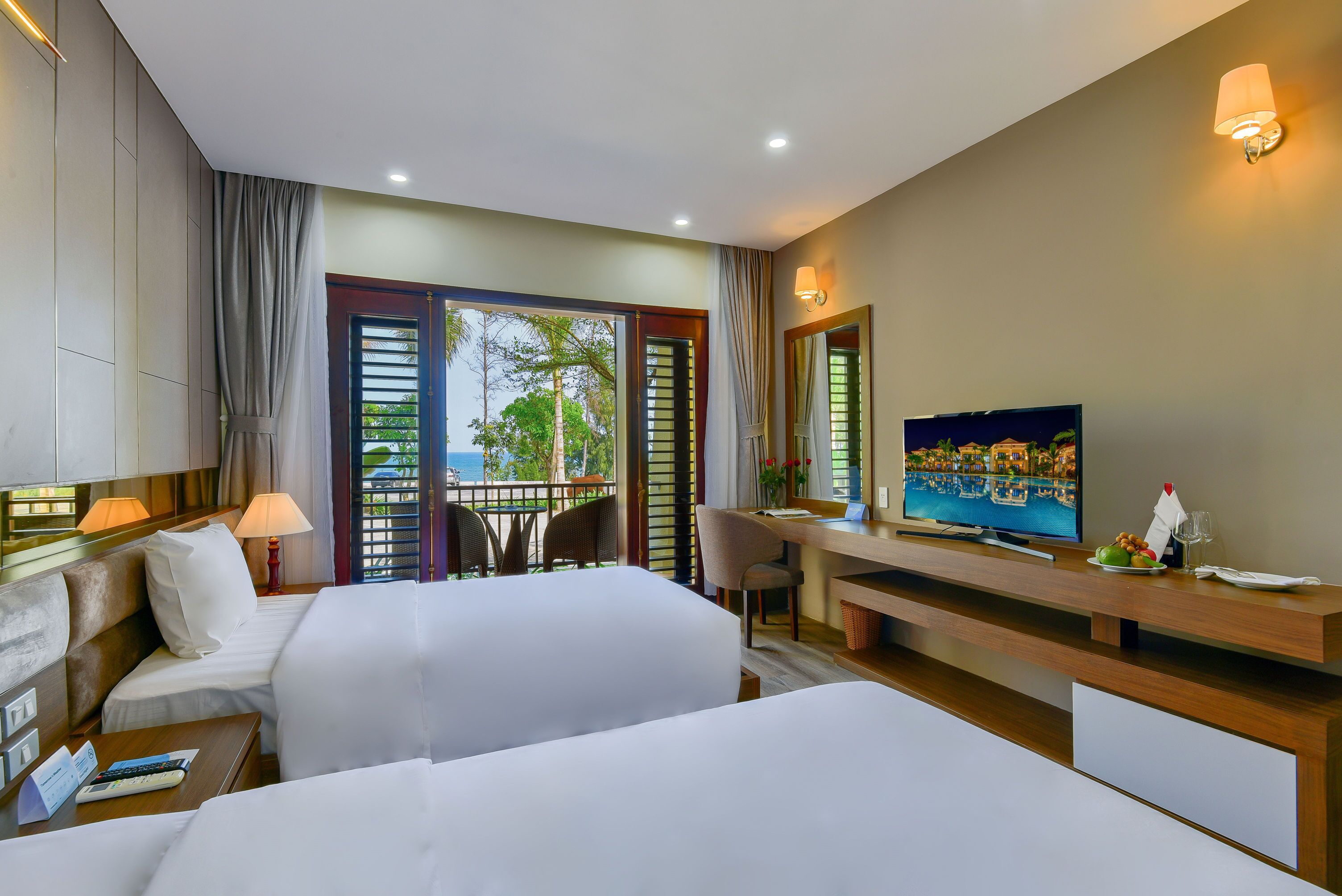 A hotel room with a bed, a desk with a computer, a TV, and a view of the outdoors.