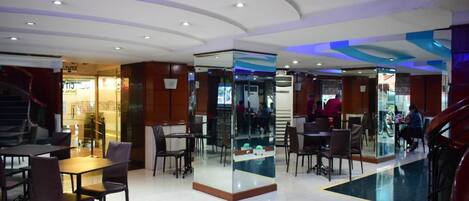 A modern hotel lobby with a central seating area, glass partitions, and a staircase.