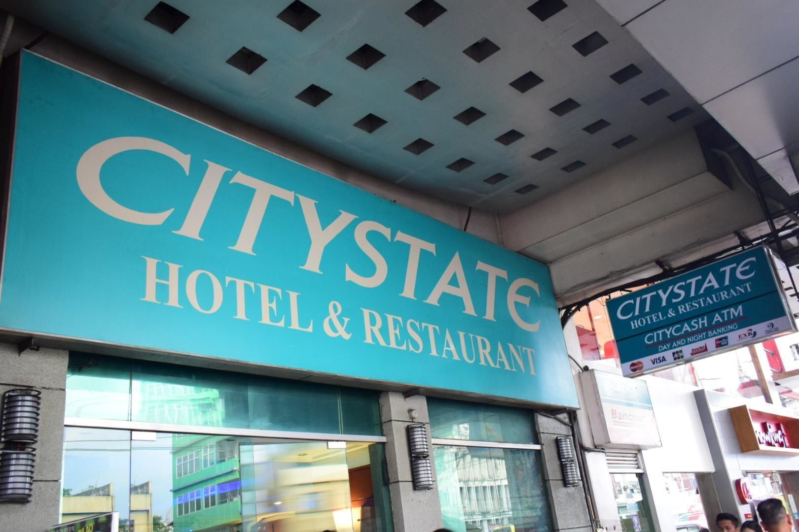 Une enseigne indiquant un hôtel et un restaurant CityState, avec, en dessous, une enseigne indiquant un distributeur automatique de billets CityCash.