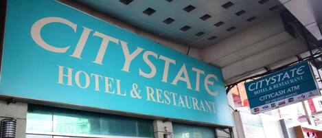 Une enseigne indiquant un hôtel et un restaurant CityState, avec, en dessous, une enseigne indiquant un distributeur automatique de billets CityCash.