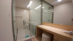 Un bany modern amb plat de dutxa de vidre, vàter i un moble de tocador amb mirall.