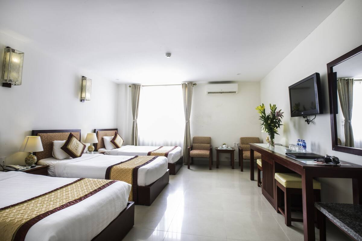 Habitación de hotel con dos camas, un escritorio, una silla, un televisor y un aire acondicionado.