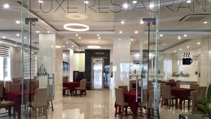A modern restaurant interior with glass partitions, multiple dining tables, and a clean, polished floor. - Luxe Hotel (Dong Hoi)