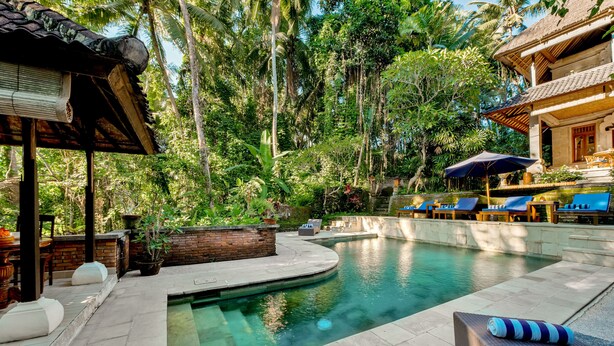 A pool area with lounge chairs, a covered seating area, and a brick planter. - Kebun Indah Ubud (Ubud)