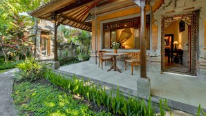 A traditional wooden pavilion with a tiled patio, surrounded by lush greenery and a stone pathway. - Kebun Indah Ubud (Ubud)