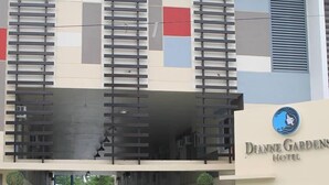 Entrada de un hotel con diseño moderno, que presenta un techo plano, una galería techada y un cartel para Dianne Gardens Hotel.